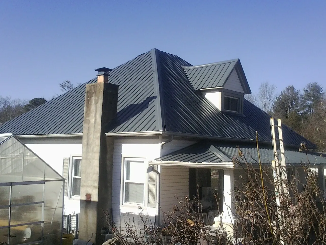 Dark blue standing seam metal roof on a white farmhouse with dormer — Slate & Tile Roof Repair by Roofing Brothers in Eagle Bridge