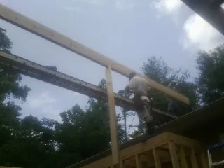 Carpenter setting a ridge beam over a new addition frame — Ice Dam Removal by Roofing Brothers in Eagle Bridge