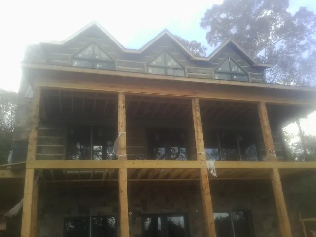 Dormers and porch framing on a large log home under construction — Roof Coating work by our crew in Eagle Bridge