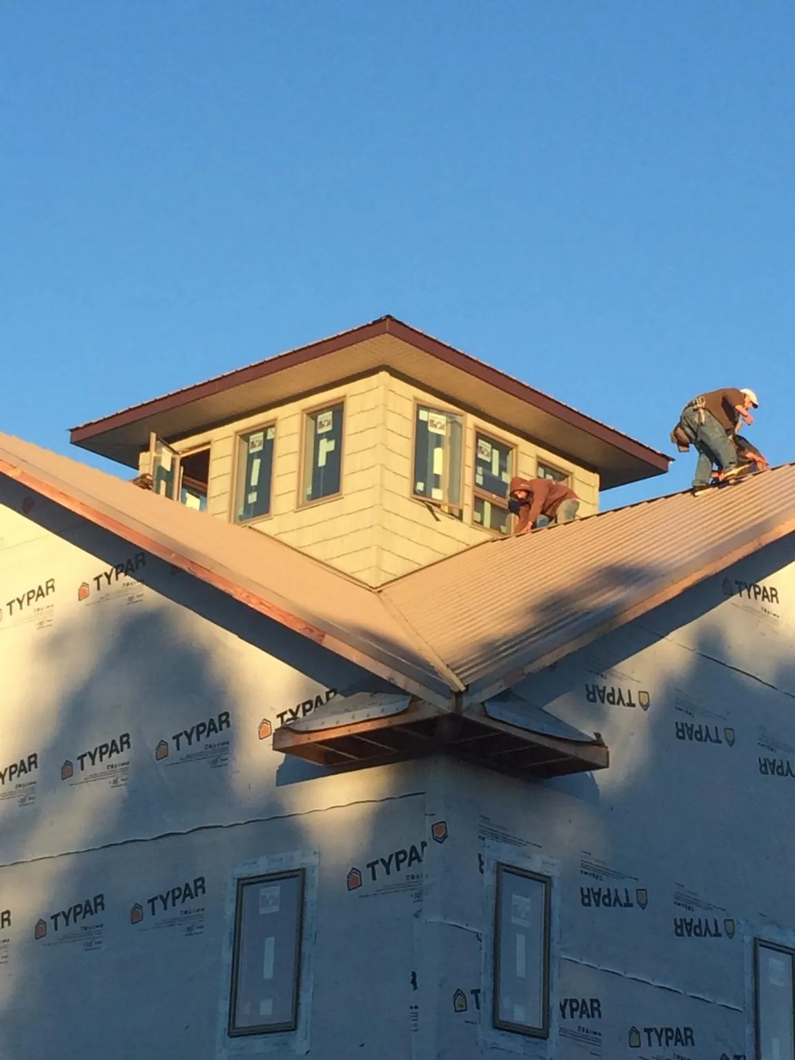 Roofers working around a rooftop cupola on a new metal roof at sunset — Roof Waterproofing in Eagle Bridge by Roofing Brothers